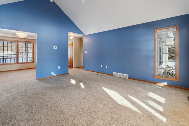 carpeted spare room with high vaulted ceiling and a chandelier