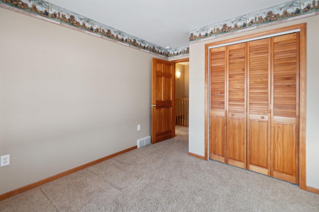 unfurnished bedroom featuring light colored carpet and a closet