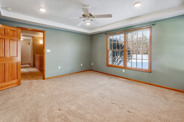 carpeted empty room with ceiling fan and a tray ceiling