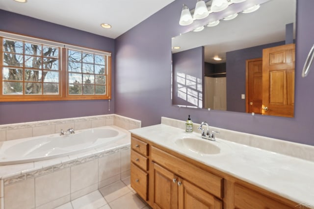 bathroom with tile patterned flooring, tiled tub, and vanity