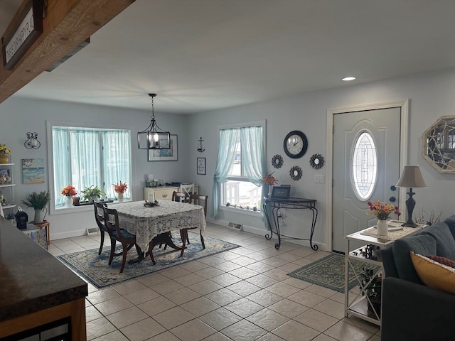 tiled dining area featuring an inviting chandelier and plenty of natural light