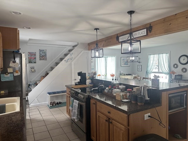 kitchen featuring hanging light fixtures, stainless steel electric stove, light tile patterned floors, black microwave, and sink