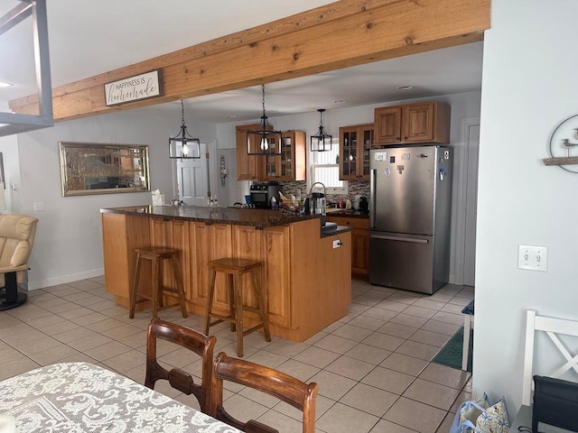 kitchen featuring a breakfast bar area, stainless steel refrigerator, kitchen peninsula, pendant lighting, and backsplash