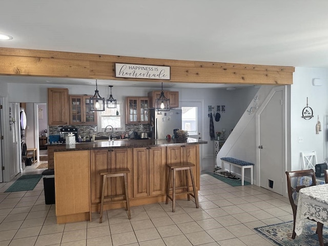 kitchen with hanging light fixtures, a breakfast bar, stainless steel fridge, plenty of natural light, and decorative backsplash