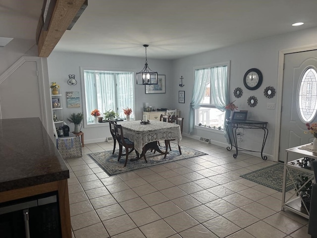 tiled dining room featuring an inviting chandelier, beam ceiling, and plenty of natural light