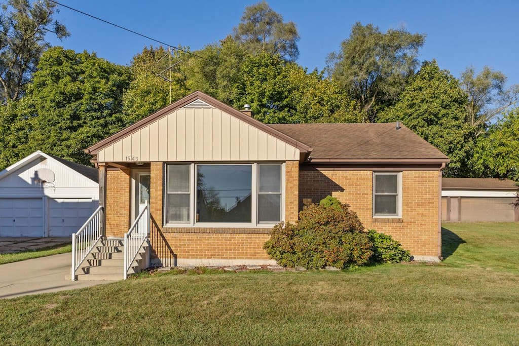 view of front of home featuring an outbuilding, a front yard, and a garage