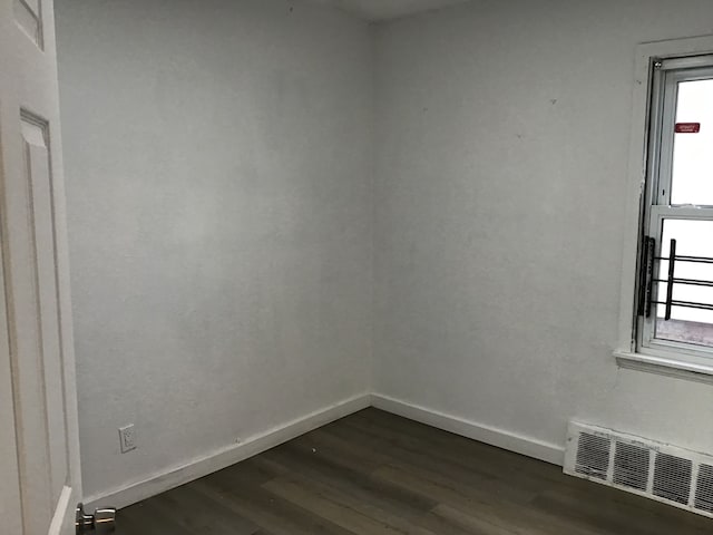 spare room featuring baseboards, visible vents, and dark wood finished floors