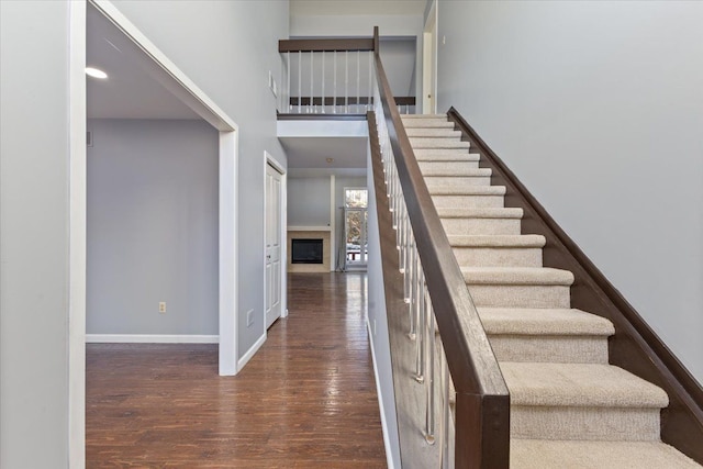 stairs with wood-type flooring and a high ceiling