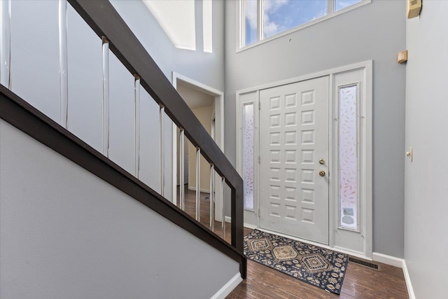 foyer with a towering ceiling and wood-type flooring