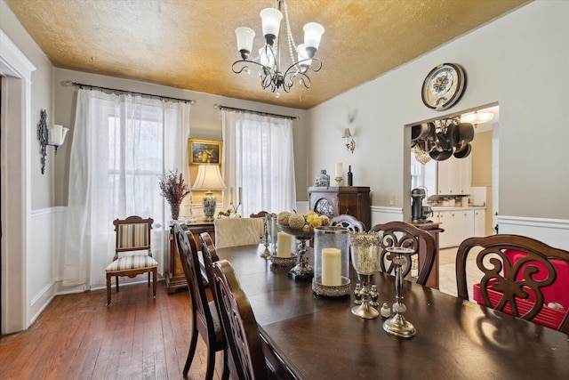 dining area featuring a notable chandelier, dark hardwood / wood-style flooring, and a textured ceiling