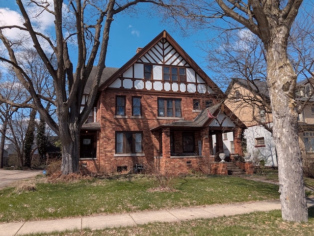 tudor house with a front yard and brick siding