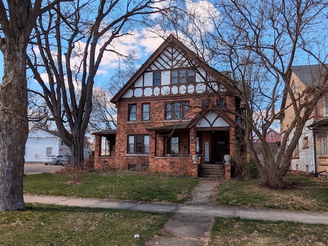 tudor home with crawl space, a front lawn, and brick siding