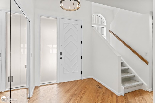 entrance foyer with light hardwood / wood-style floors and a notable chandelier