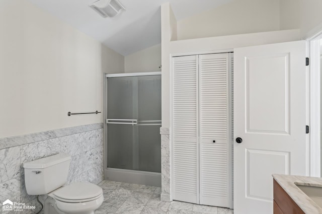 bathroom with tile walls, a shower with door, lofted ceiling, and toilet