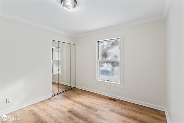 empty room with ornamental molding and light wood-type flooring