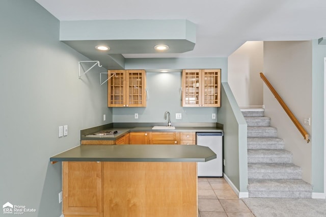 kitchen with kitchen peninsula, dishwasher, light tile patterned floors, and sink