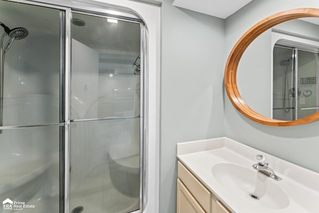 bathroom featuring a shower with door and vanity