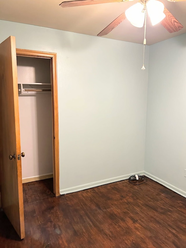 unfurnished bedroom with an AC wall unit, dark hardwood / wood-style floors, ceiling fan, and a closet