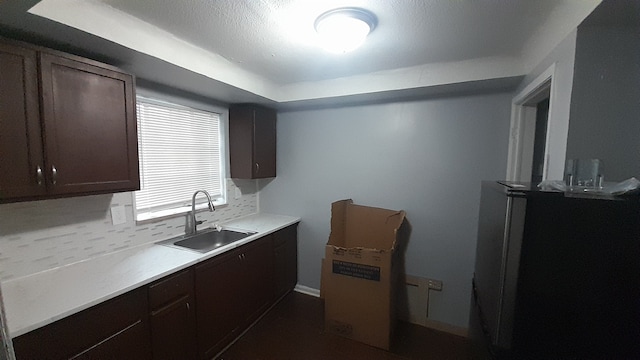 kitchen featuring sink, dark brown cabinets, and backsplash