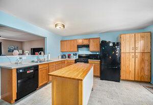 kitchen with sink, black appliances, kitchen peninsula, and a kitchen island