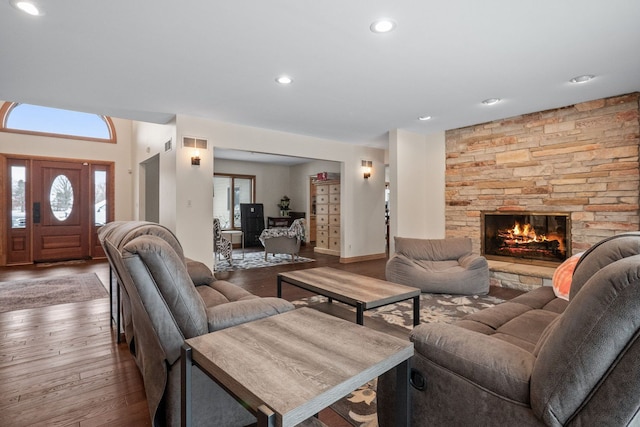 living room with wood-type flooring and a stone fireplace