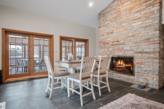 unfurnished dining area with french doors, a healthy amount of sunlight, a fireplace, and lofted ceiling