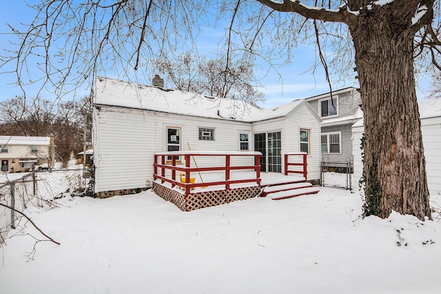 snow covered rear of property with a deck