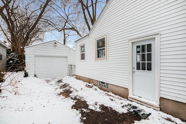 view of snowy exterior with a garage and an outdoor structure