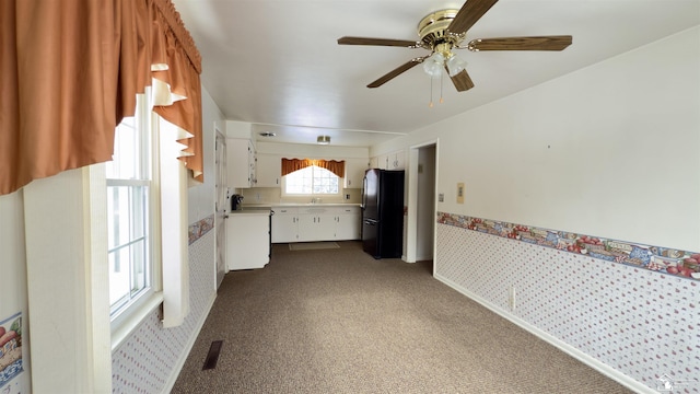 interior space with ceiling fan, black refrigerator, and carpet floors