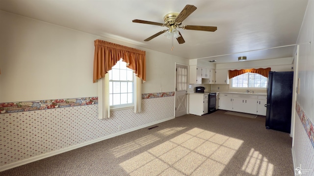 kitchen featuring white cabinets, black refrigerator, ceiling fan, carpet floors, and electric stove