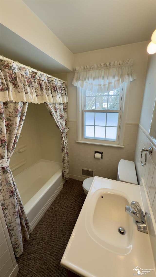 full bathroom with tile walls, shower / bath combo with shower curtain, sink, and toilet