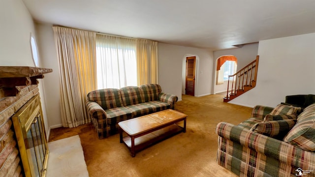 carpeted living room featuring a stone fireplace