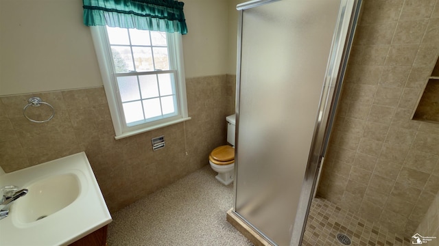 bathroom featuring toilet, an enclosed shower, vanity, and tile walls