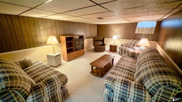 sitting room featuring a paneled ceiling, wooden walls, and carpet flooring