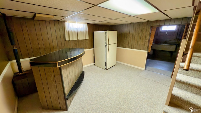 interior space featuring white refrigerator, a paneled ceiling, and wood walls