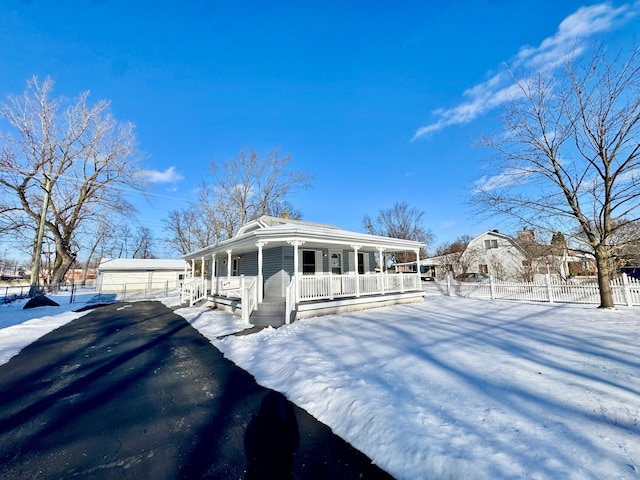 view of front facade with a porch, a garage, and an outbuilding