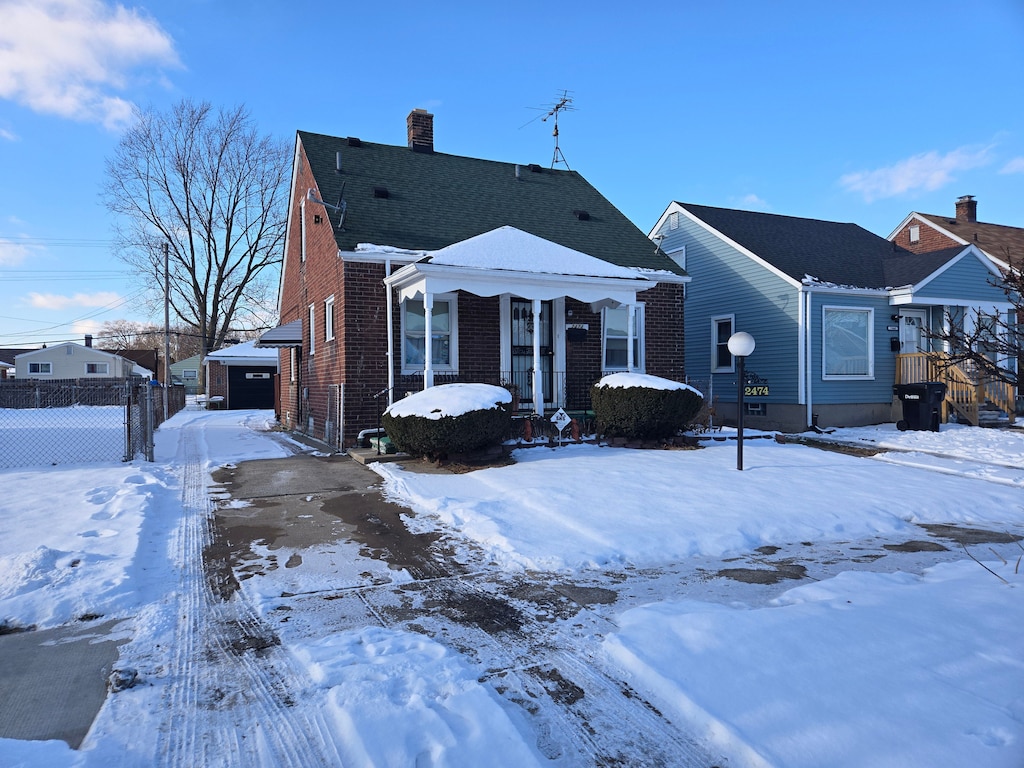 snow covered rear of property featuring a garage