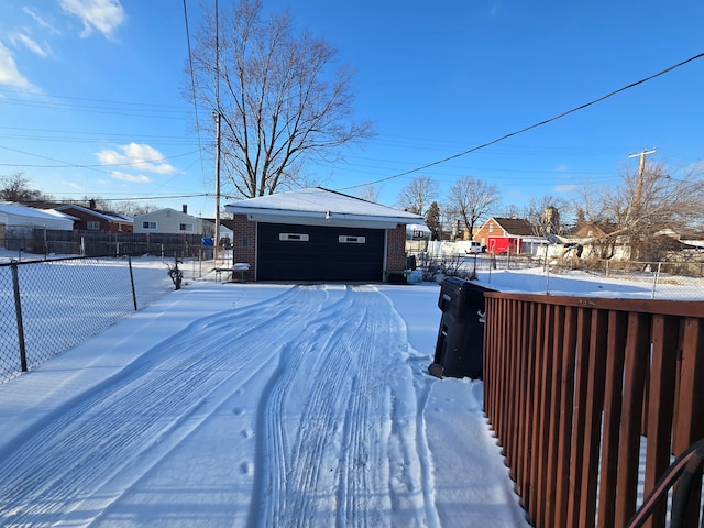 yard covered in snow featuring a garage and an outbuilding