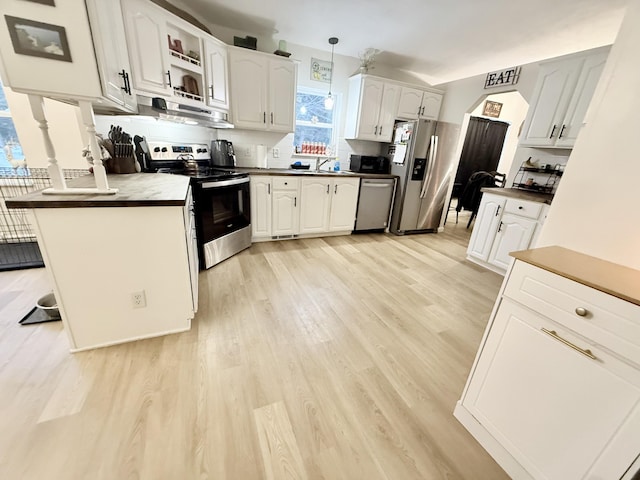 kitchen featuring light hardwood / wood-style floors, stainless steel appliances, white cabinets, decorative light fixtures, and tasteful backsplash