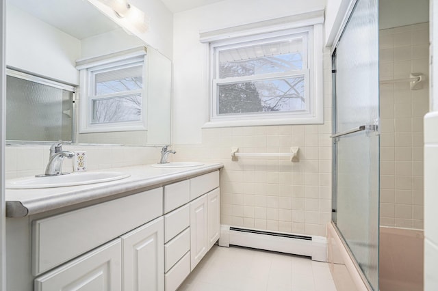 bathroom featuring enclosed tub / shower combo, vanity, tile walls, a healthy amount of sunlight, and a baseboard radiator