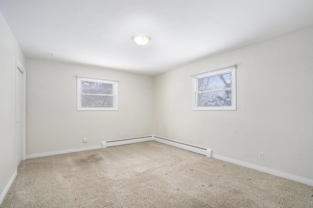 carpeted spare room with a baseboard heating unit and a wealth of natural light