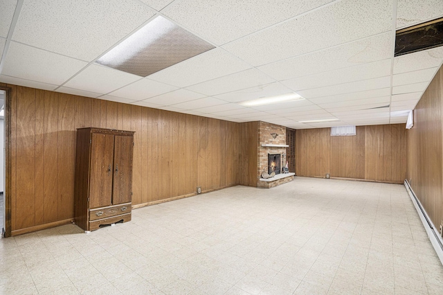 basement with a fireplace, a drop ceiling, and wood walls