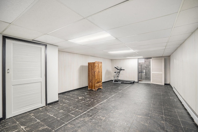 basement with a baseboard radiator and a drop ceiling