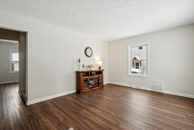 unfurnished room featuring a textured ceiling and dark hardwood / wood-style flooring