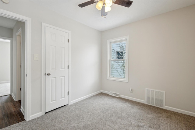 spare room with dark colored carpet and ceiling fan