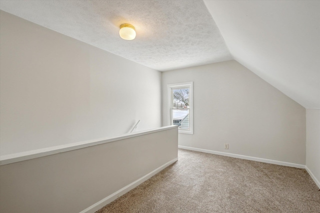 additional living space with lofted ceiling, a textured ceiling, and carpet flooring