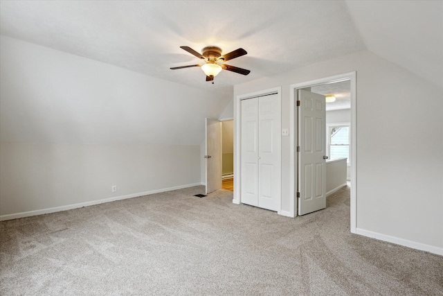 unfurnished bedroom featuring light carpet, ceiling fan, and vaulted ceiling