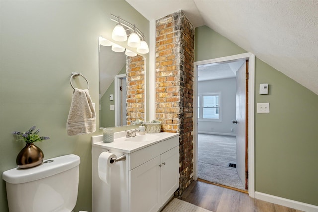 bathroom featuring toilet, a textured ceiling, vaulted ceiling, hardwood / wood-style floors, and vanity