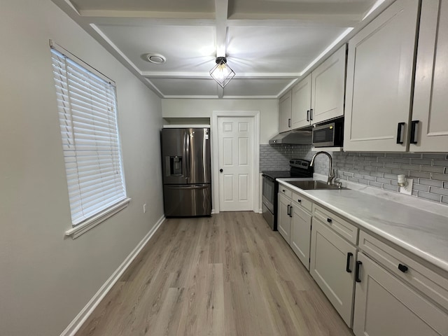 kitchen featuring appliances with stainless steel finishes, a healthy amount of sunlight, light hardwood / wood-style floors, sink, and backsplash