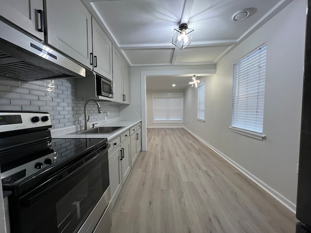 kitchen featuring range hood, sink, white cabinetry, light hardwood / wood-style flooring, and stainless steel appliances